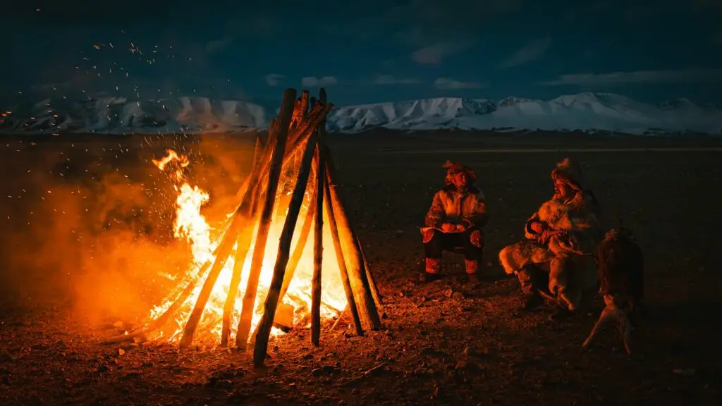 Des hommes de la Mongolie assis autour d'un feu de camp au crépuscule.